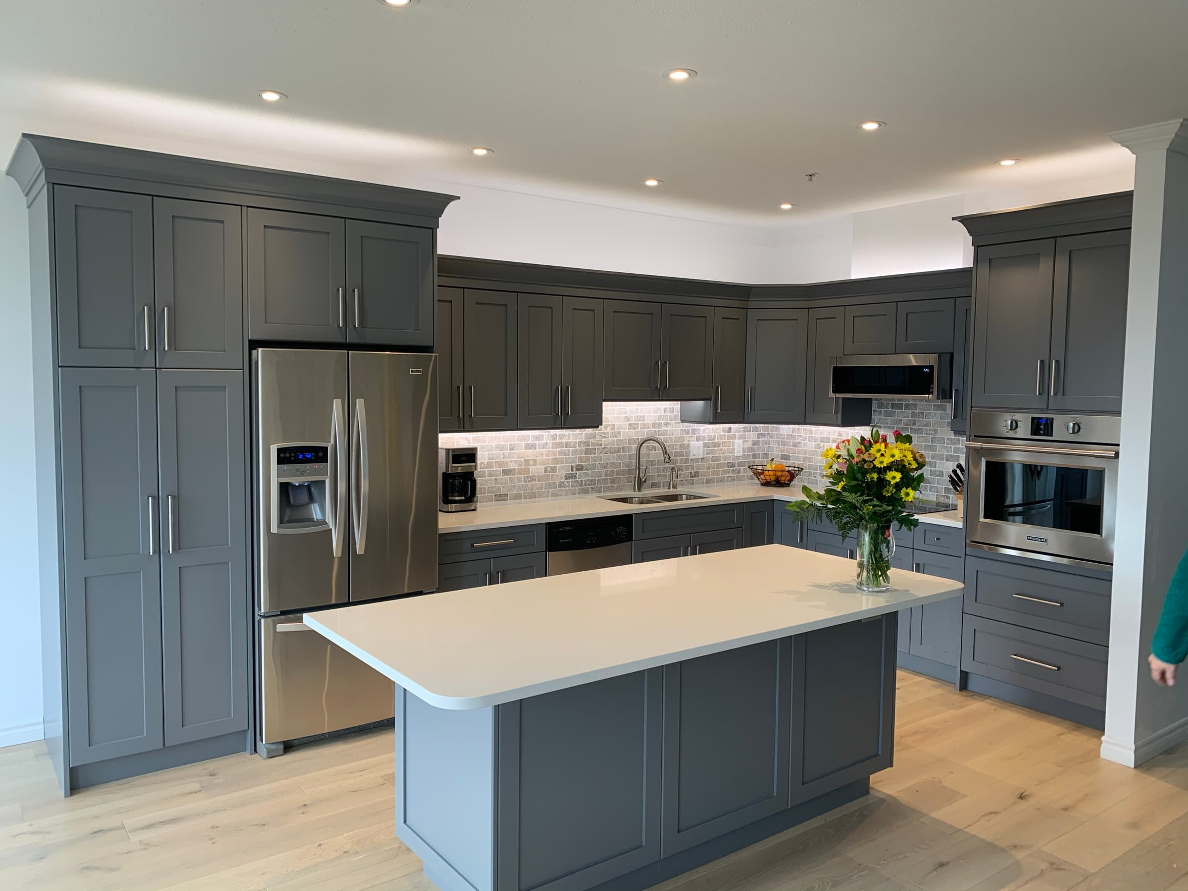 Charcoal shaker kitchen with marble backsplash, oversized white quartz island and warm light oak floors
