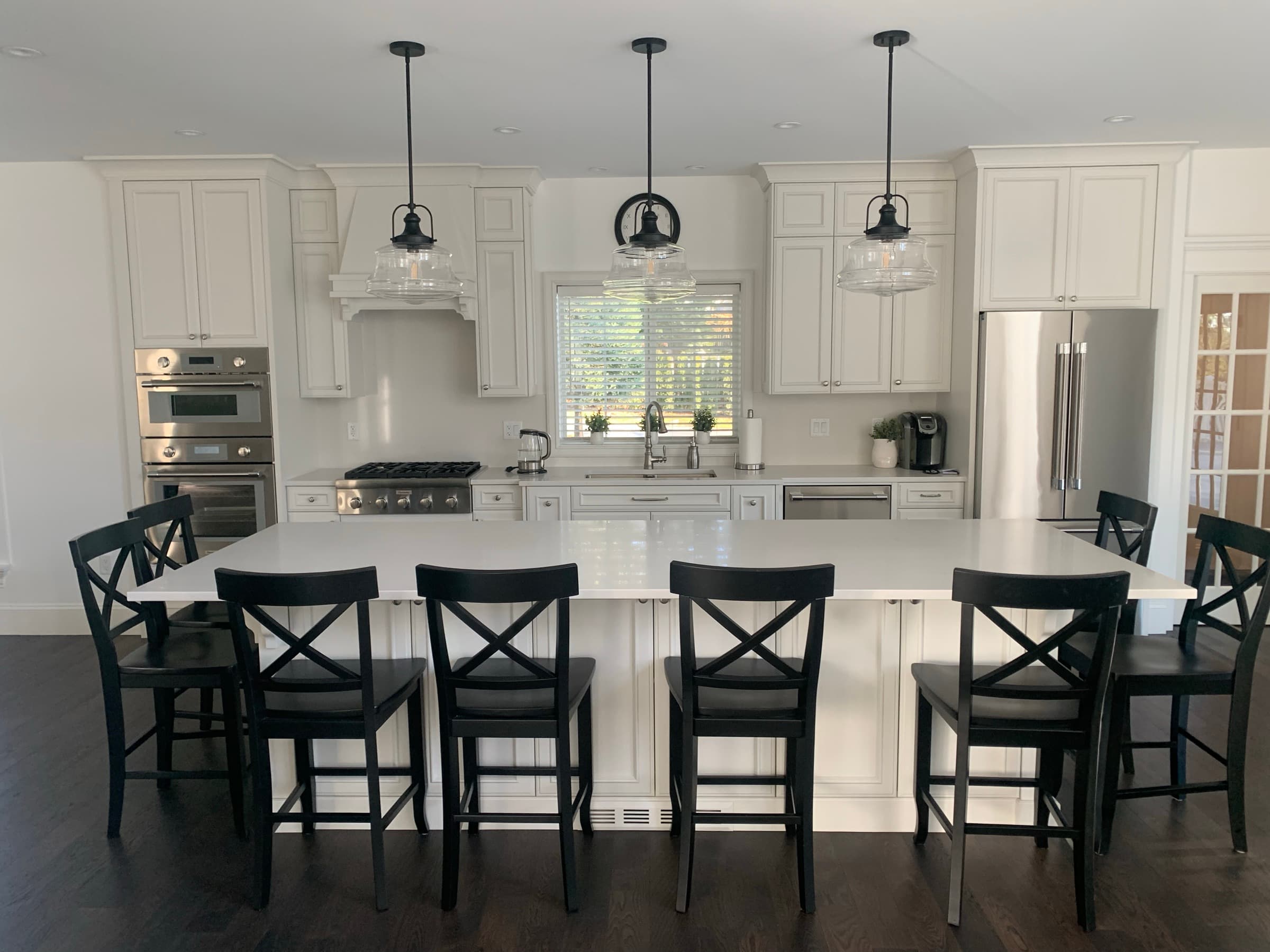 White kitchen with large island seating six, triple pendants and double wall oven — Abbotsford BC